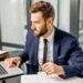 Professional man reviewing documents and working on laptop, representing analysis of the advanced premium tax credit and health insurance costs.